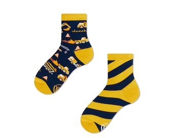 Könnte beinhalten: Ein Paar Kniestrümpfe. Eine Socke hat einen blauen Hintergrund mit gelben Baufahrzeugen und Kegeln. Die andere Socke hat einen gelben Hintergrund mit blauen diagonalen Streifen.