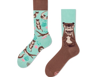 May include: A pair of colorful socks with a teal background and brown otters. One sock features a mother otter holding a baby otter. The other sock has multiple otters swimming in a teal and white pattern.