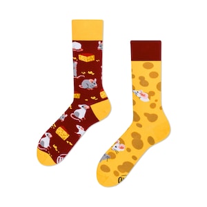 May include: A pair of socks with a mouse and cheese design. One sock is red with a pattern of mice and cheese blocks. The other sock is yellow with a pattern of cheese holes and mice.