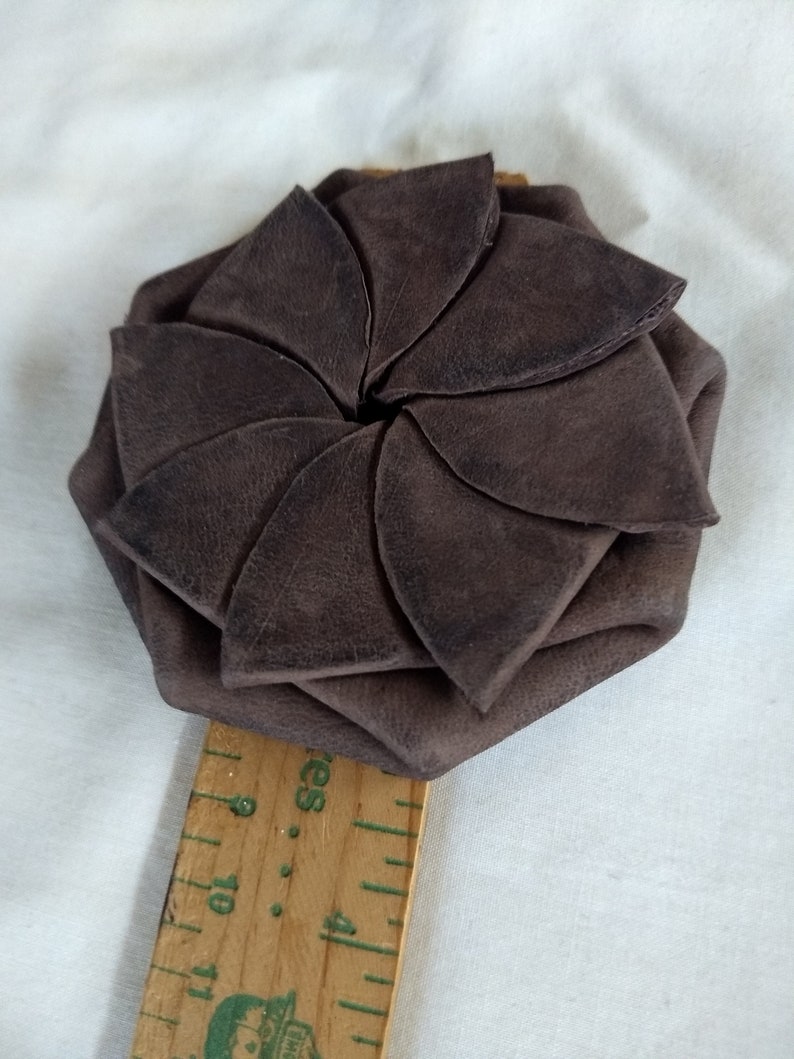 May include: A brown leather coin purse with a flower-shaped design. The purse is closed and the petals are folded inwards.