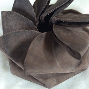 May include: A brown leather coin purse folded into a flower shape.