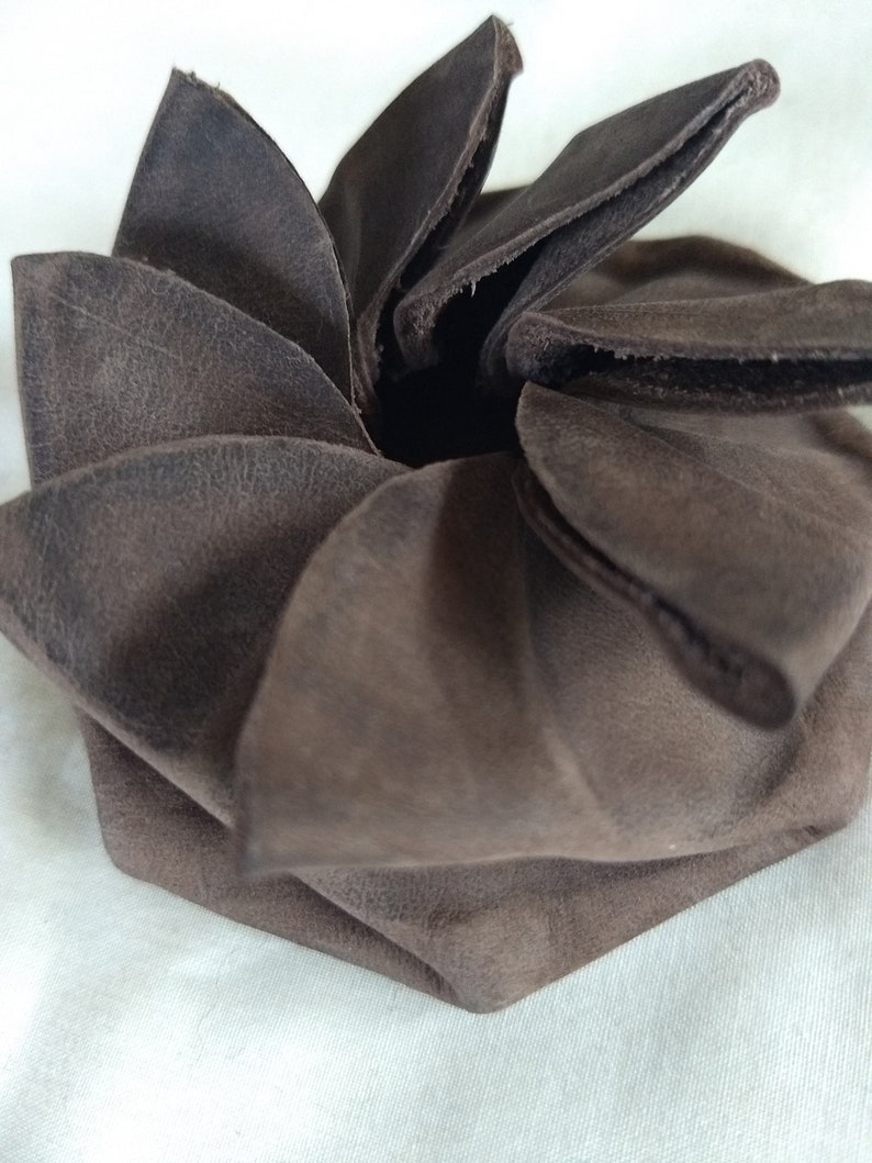 May include: A brown leather coin purse folded into a flower shape.