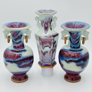May include: Three decorative ceramic vases with a blue and purple glaze. The vases have a unique, swirling pattern and are decorated with handles.