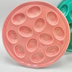 May include: A pink ceramic egg plate with 12 individual indentations for serving deviled eggs.