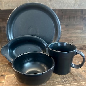 May include: A set of black ceramic dinnerware, including a large plate, a small bowl, a serving dish, and a mug.