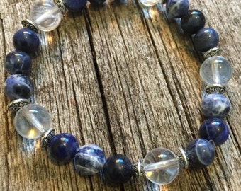 May include: A blue and clear crystal beaded bracelet with silver accents. The bracelet is made with round beads and is strung on elastic.