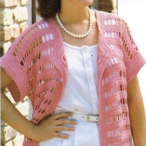 Puede incluir: Un cárdigan de crochet rosa de corte holgado y mangas cortas. El cárdigan tiene un delicado patrón de calado y un cuello chal.