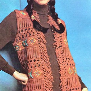 May include: A brown macrame vest with fringe and geometric patterns. The vest features square designs with turquoise, orange, and yellow accents. The model is wearing a brown turtleneck and headband.