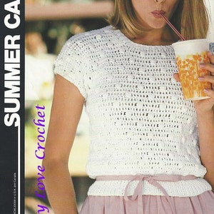 May include: A white crochet top with a round neckline and short sleeves. The top is tied at the waist with a matching white ribbon. The model is wearing a pink skirt.