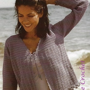 May include: A light purple crocheted cardigan with a tie at the neckline and a scalloped edge. The cardigan is worn over a white tank top and a floral print skirt.