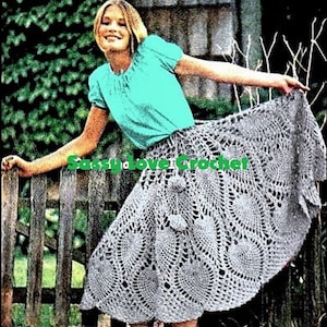 May include: A woman wearing a turquoise top and a gray crochet skirt with a scalloped hem. The skirt has a pineapple design and is worn with a belt.