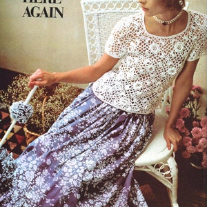 May include: A woman wearing a white crocheted top with a floral pattern and a long, flowing skirt with a floral pattern. The text "PRETTY CLOTHES ARE HERE AGAIN" is visible in the background.