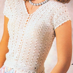 May include: White crochet top with a V-neck and short sleeves. The top has a delicate, lacy pattern.