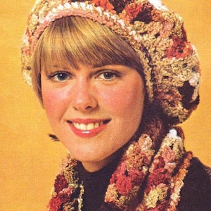 May include: A woman wearing a crocheted hat and scarf in shades of pink, brown, and white. The hat is a beret style and the scarf is a long, flowing style.
