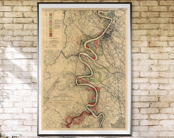 May include: A vintage map of the Missouri River, printed in black, red, green, and blue on a cream-colored background. The map is framed in a black frame and hanging on a brick wall.