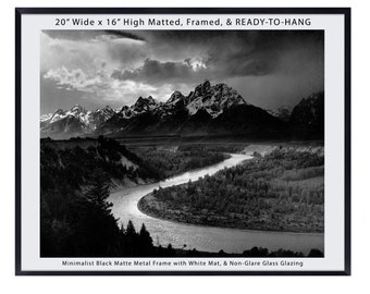 May include: Black and white photograph of a mountain range with a river winding through the valley. The image is framed in a black matte metal frame with a white mat and non-glare glass glazing. The frame is 20 inches wide and 16 inches high.