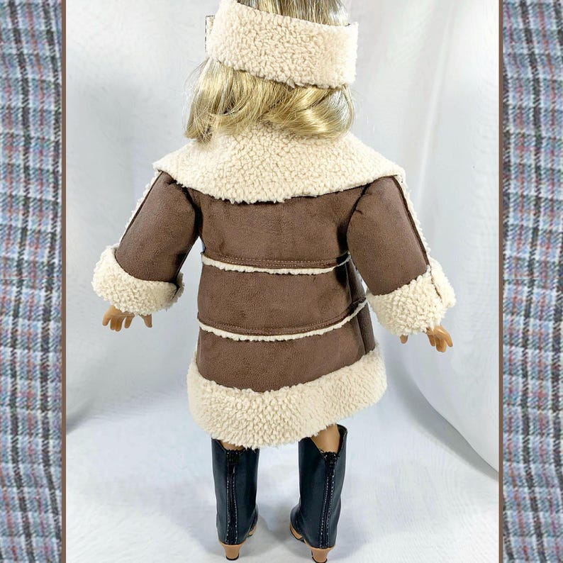 May include: A brown faux fur coat with a white faux fur trim and collar. The coat is worn by a doll and has a zipper closure.