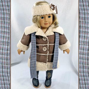 May include: A brown faux fur coat with a white faux fur collar and cuffs. The coat has a plaid scarf and a white headband with a brown flower accent. The doll is wearing black boots.