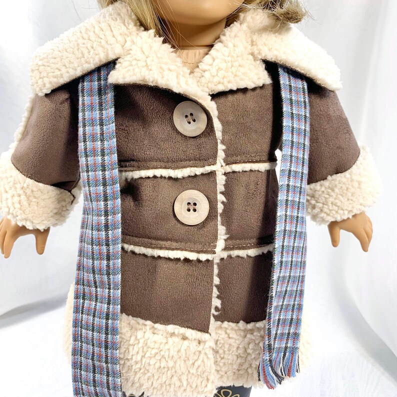 May include: A brown faux fur coat with a white sherpa collar and trim. The coat has a plaid scarf and three large brown buttons.