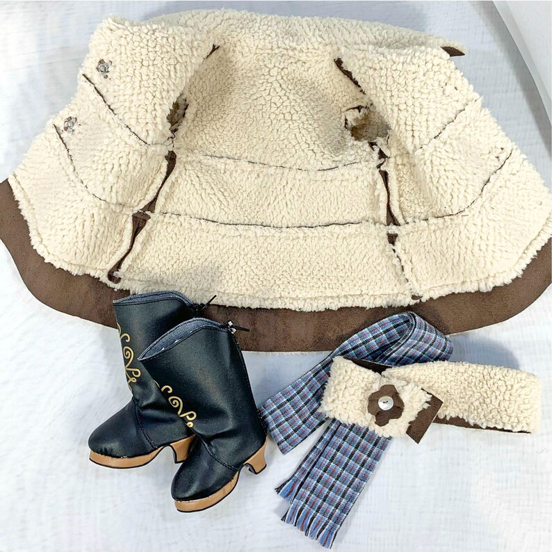 May include: A brown faux fur vest with a sherpa lining, a pair of black leather boots with gold embroidery, and a blue and white plaid scarf with a brown button.