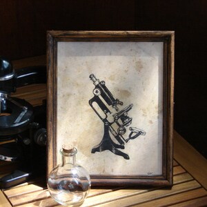 May include: A black microscope with a round stage and a single lens is pictured in front of a framed illustration of a vintage microscope. The illustration is in black and white and shows a microscope with a long, curved arm and a round stage.