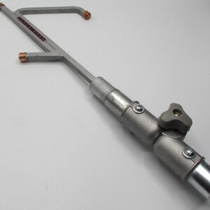 May include: A silver metal extendable arm with a swivel joint and a knob for adjusting the angle. The arm has a threaded end for attaching to a camera or other device.