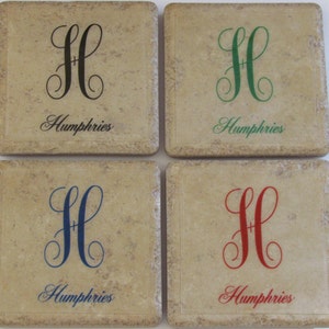 Puede incluir: Conjunto de cuatro posavasos cuadrados de cerámica con fondo beige. Cada posavasos presenta una letra "H" cursiva negra, verde, azul o roja con un diseño de espiral y la palabra "Humphries" en cursiva debajo de la letra.