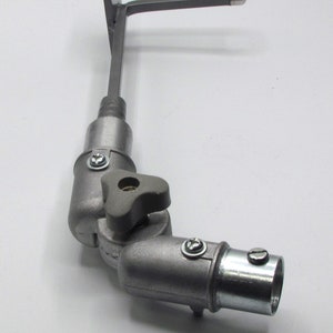 May include: A silver metal adjustable arm with a flat plate on one end and a threaded connector on the other. The arm has a knob for adjusting the angle.