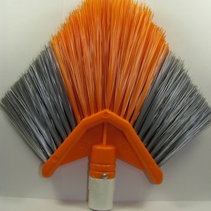 Könnte beinhalten: Orangefarbener und grauer Winkelbesen mit einem weißen Kunststoffgriff. Der Besen hat eine fächerförmige Form mit Borsten, die sich in einem weiten Bogen ausbreiten.