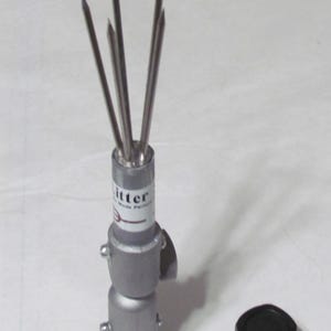 May include: A metal ice splitter with multiple sharp prongs, a gray body, and a black cap. The ice splitter has the word "litter" printed on it.