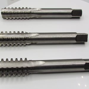 Può includere: Tre set di maschi e matrici in metallo argentato con manici quadrati.