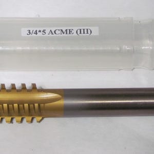 Puede incluir: Un macho de metal con un extremo de corte dorado y un vástago plateado. El macho está etiquetado "3/4*5 ACME (III)" y va acompañado de una funda de plástico transparente.