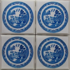 Puede incluir: Conjunto de cuatro posavasos de cerámica blanca con un patrón de sauce azul y blanco. Cada posavasos presenta un diseño circular con una imagen central de un sauce llorón, una pagoda y un barco.