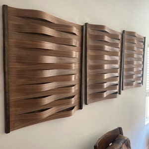 Może przedstawiać: Trzy drewniane panele ścienne z falistym, tkanym wzorem. Panele są wykonane z jasnobrązowego drewna i są ułożone w rzędzie na białej ścianie.