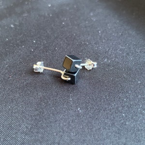 May include: A pair of black cube stud earrings with silver posts.