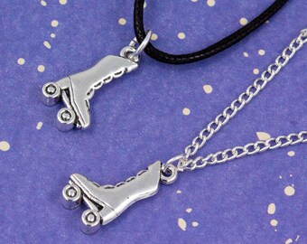May include: Two silver roller skate charm necklaces. One necklace has a black cord and the other has a silver chain.