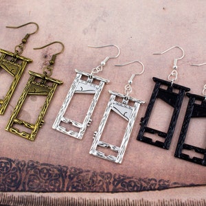 Puede incluir: Un conjunto de tres pares de pendientes en forma de guillotina. Los pendientes est&aacute;n hechos de metal y vienen en plata, oro y negro.