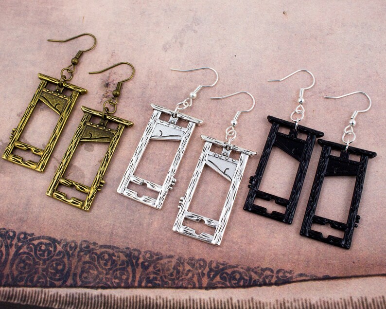Puede incluir: Un conjunto de tres pares de pendientes en forma de guillotina. Los pendientes est&aacute;n hechos de metal y vienen en plata, oro y negro.