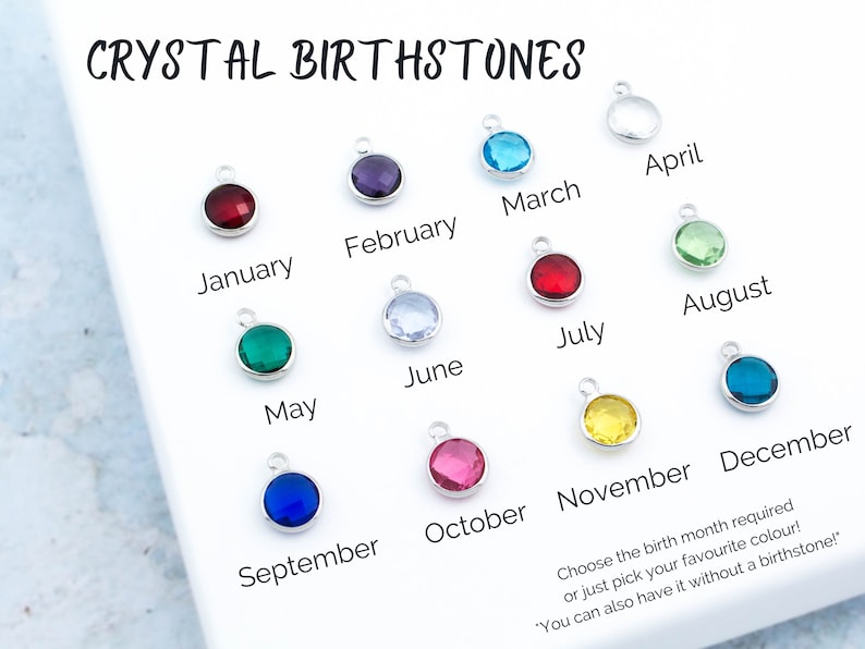 May include: A set of 12 crystal birthstones, each representing a different month of the year. The stones are displayed on a white surface with the corresponding month name written below each stone. The text "CRYSTAL BIRTHSTONES" is at the top of the image. The text "Choose the birth month required or just pick your favorite color!" is at the bottom of the image.