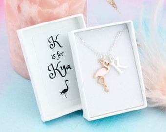 May include: A white gift box with a pink flamingo charm necklace inside. The box has a black and white illustration of a flamingo and the text "K is for Kya".
