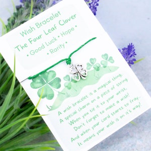 May include: Green string bracelet with a silver four-leaf clover charm. The card reads "Wish Bracelet The Four Leaf Clover • Good Luck • Hope • Rarity. A wish bracelet is a magical thing, A special charm on a piece of string. When you tie it to your wrist, Don't forget to make a wish! And when your cord starts to fray.... It means your wish is on it's way!"