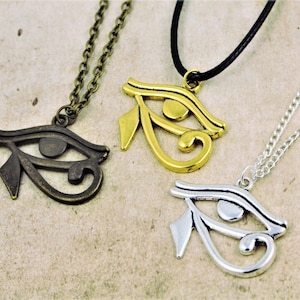 May include: Three necklaces with the Eye of Horus pendant. The pendants are made of silver, gold, and bronze. The necklaces are on a white background.