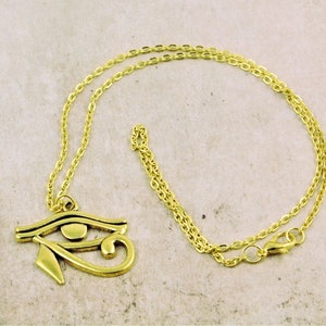 May include: A gold chain necklace with a gold pendant in the shape of the Eye of Horus.