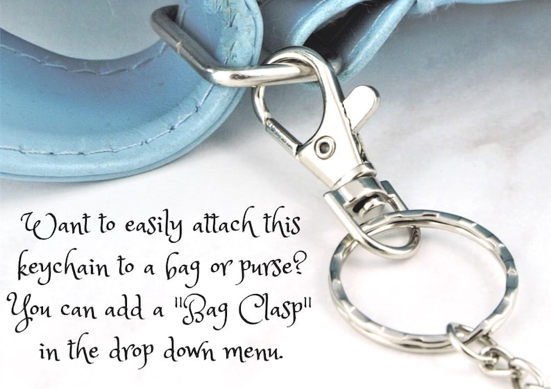 Puede incluir: Un llavero plateado con un cierre y un anillo. El texto "Want to easily attach this keychain to a bag or purse? You can add a "Bag Clasp" in the drop down menu." es visible en la imagen.