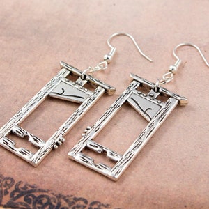 Puede incluir: Un par de pendientes de plata con forma de guillotina. Los pendientes tienen una superficie texturizada y est&aacute;n dise&ntilde;ados para parecer un instrumento de tortura medieval.