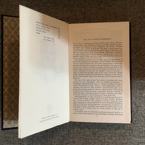 May include: A close-up of a book's interior pages with text about Ralph Waldo Emerson, an American essayist, poet, and philosopher. The text discusses his life, education, and career. The book is printed in Great Britain by Collins Clear-Type Press.