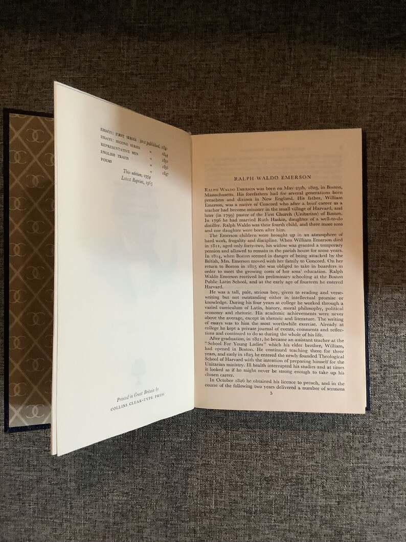 May include: A close-up of a book's interior pages with text about Ralph Waldo Emerson, an American essayist, poet, and philosopher. The text discusses his life, education, and career. The book is printed in Great Britain by Collins Clear-Type Press.