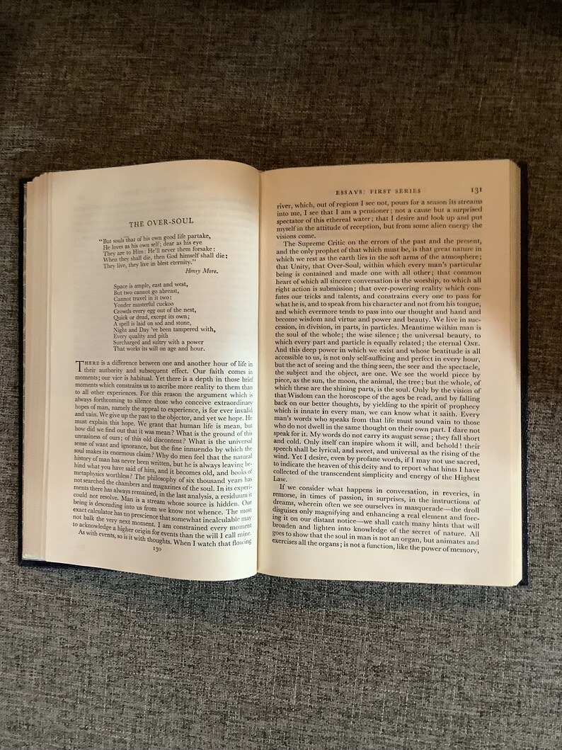 May include: An open book with a tan leather cover and yellowed pages. The book is titled "Essays: First Series" and the text on the page discusses the concept of the "Over-Soul".