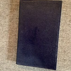 May include: A dark blue, textured, rectangular notebook.