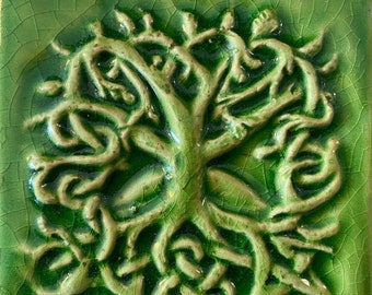 May include: Square green ceramic tile with a raised, light green tree of life design. The tree features intertwined branches and roots, with a textured, crackled surface. The tile is a vibrant shade of green.
